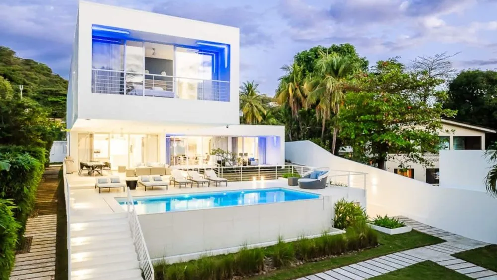 Modern two-story house with large windows and a pool in the backyard.