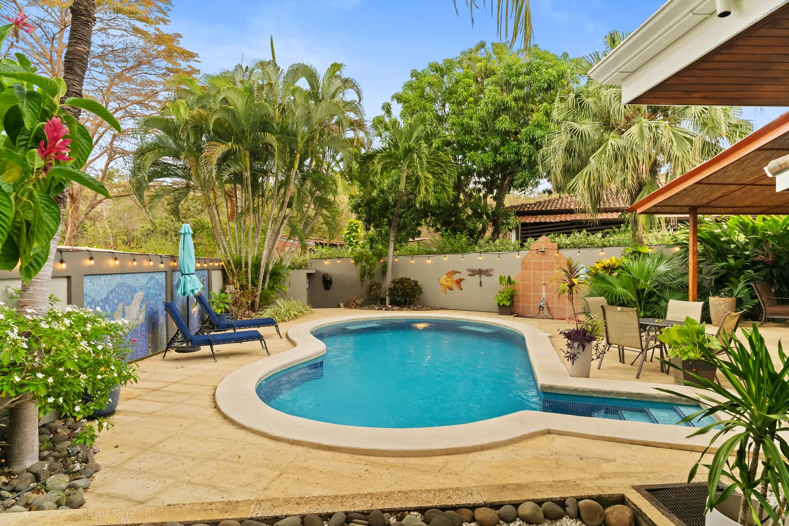 Large family villa with tropical pool, lounge chairs, and lush Guanacaste greenery — Zindis multi-suite vacation rental