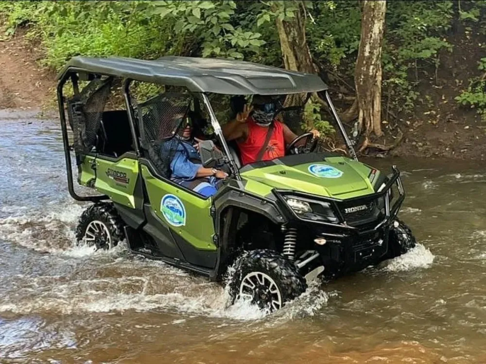 a green motorcycle parked on the side of a river